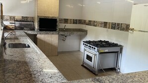 A kitchen with granite countertops, a built-in oven, and a gas range. - Chácara Inribas accommodation and events - Goiânia - GO. (Goiânia)