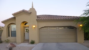 A two-story house with a beige facade, a tiled roof, and a garage.