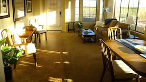 A well-lit living room with a dining area, featuring a sofa, chairs, a coffee table, and a dining table.