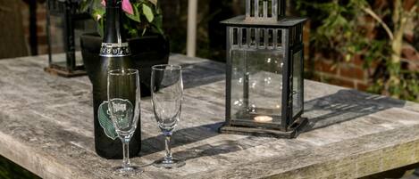 A wooden table with a bottle of wine, two glasses, and a lantern.