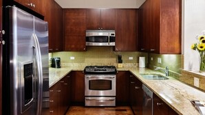 A modern kitchen with stainless steel appliances, wooden cabinets, and a green tiled backsplash. - Wrigley Field All Star Suite 3 Bedrooms 2 Bath (Chicago)