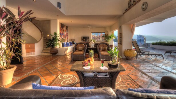 Amplia sala de estar con una escalera curva, asientos cómodos y ventanas grandes que ofrecen vistas de la ciudad.