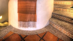 Una escalera de caracol con una lámpara de mosaico en la parte superior, un muro con diseño y una ventana con vistas.