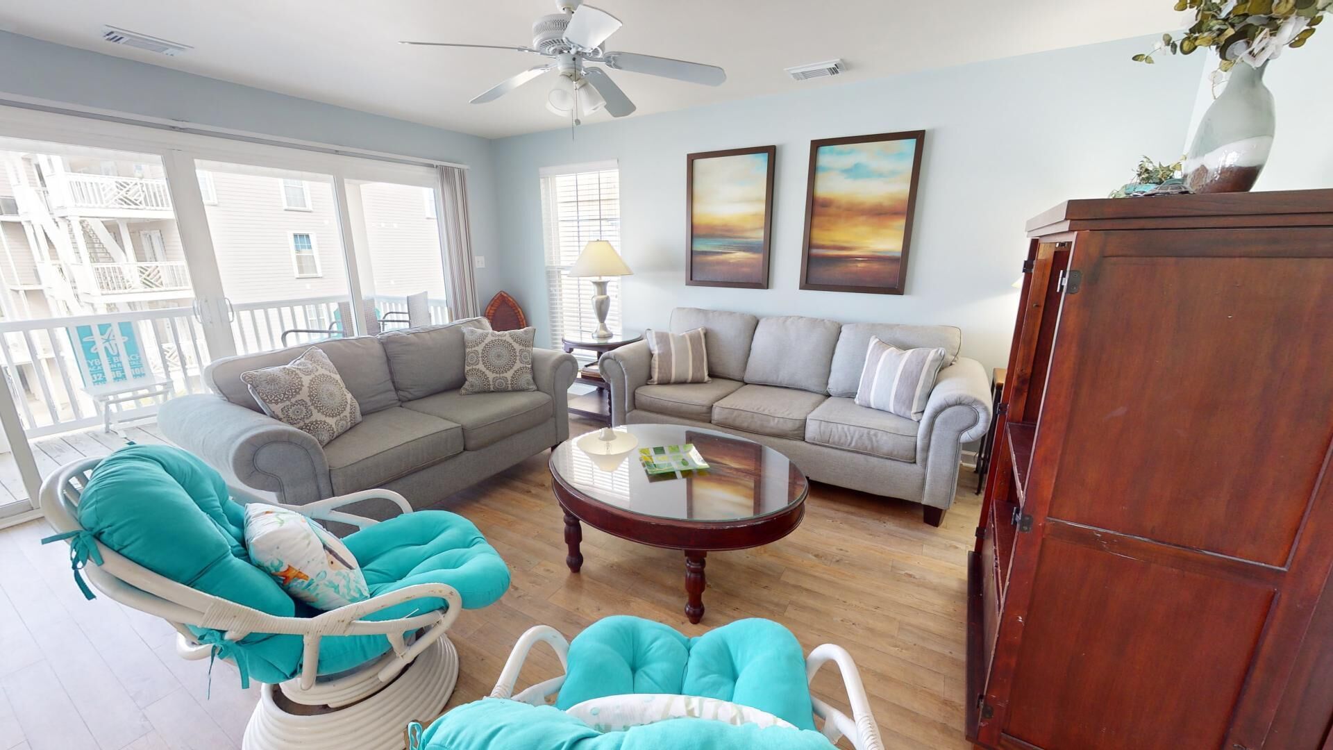 A living room with a sofa, chairs, a coffee table, and a ceiling fan.