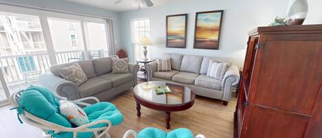 A living room with a sofa, chairs, a coffee table, and a ceiling fan.