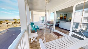 A wooden deck with a swing chair, a small table, and a chair.