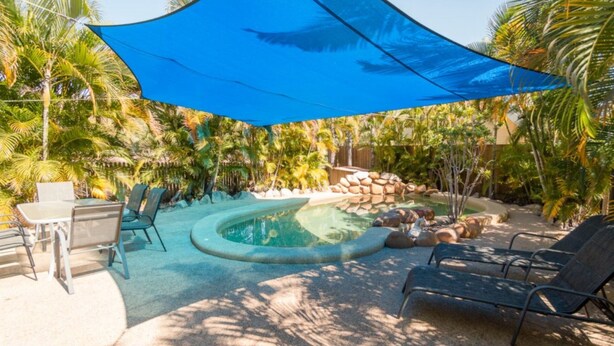 Ein Garten mit Schwimmbad, Liegestühlen und einem Tisch.