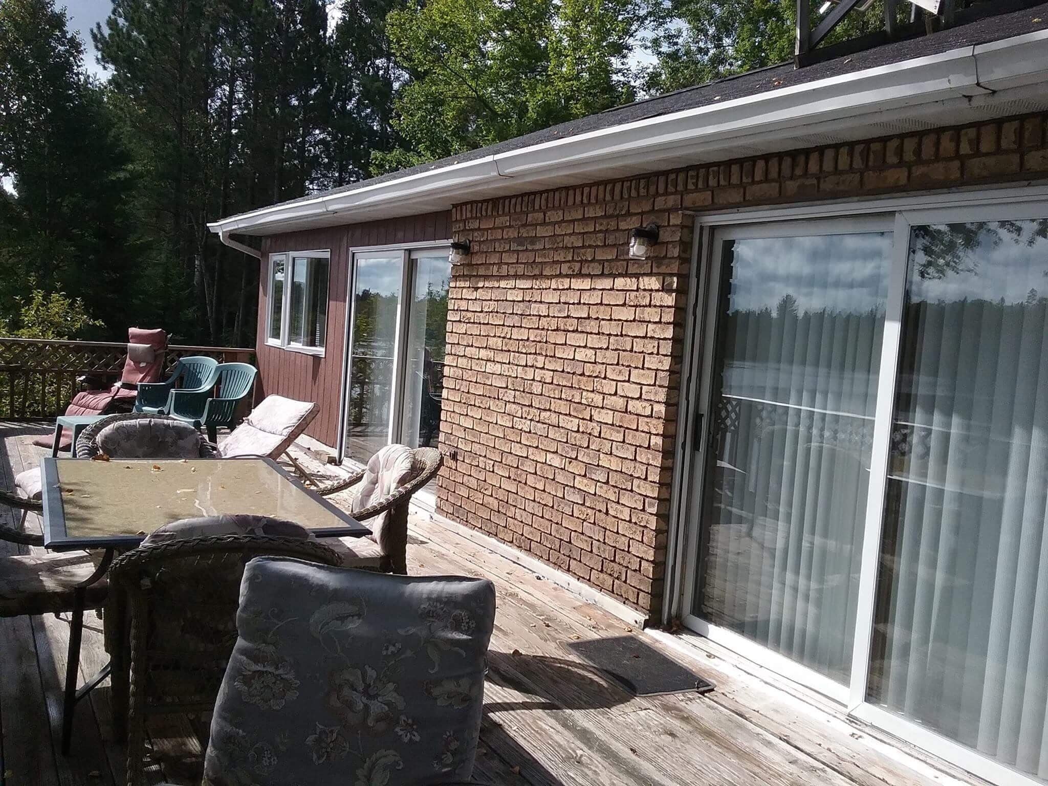 A covered patio with outdoor furniture, a brick wall, and a sliding glass door.