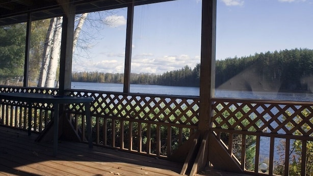 Puinen terassi, jossa on koristeellinen kaiderakenteinen reunus, ja jolta avautuu näkymä järvelle ja metsään.