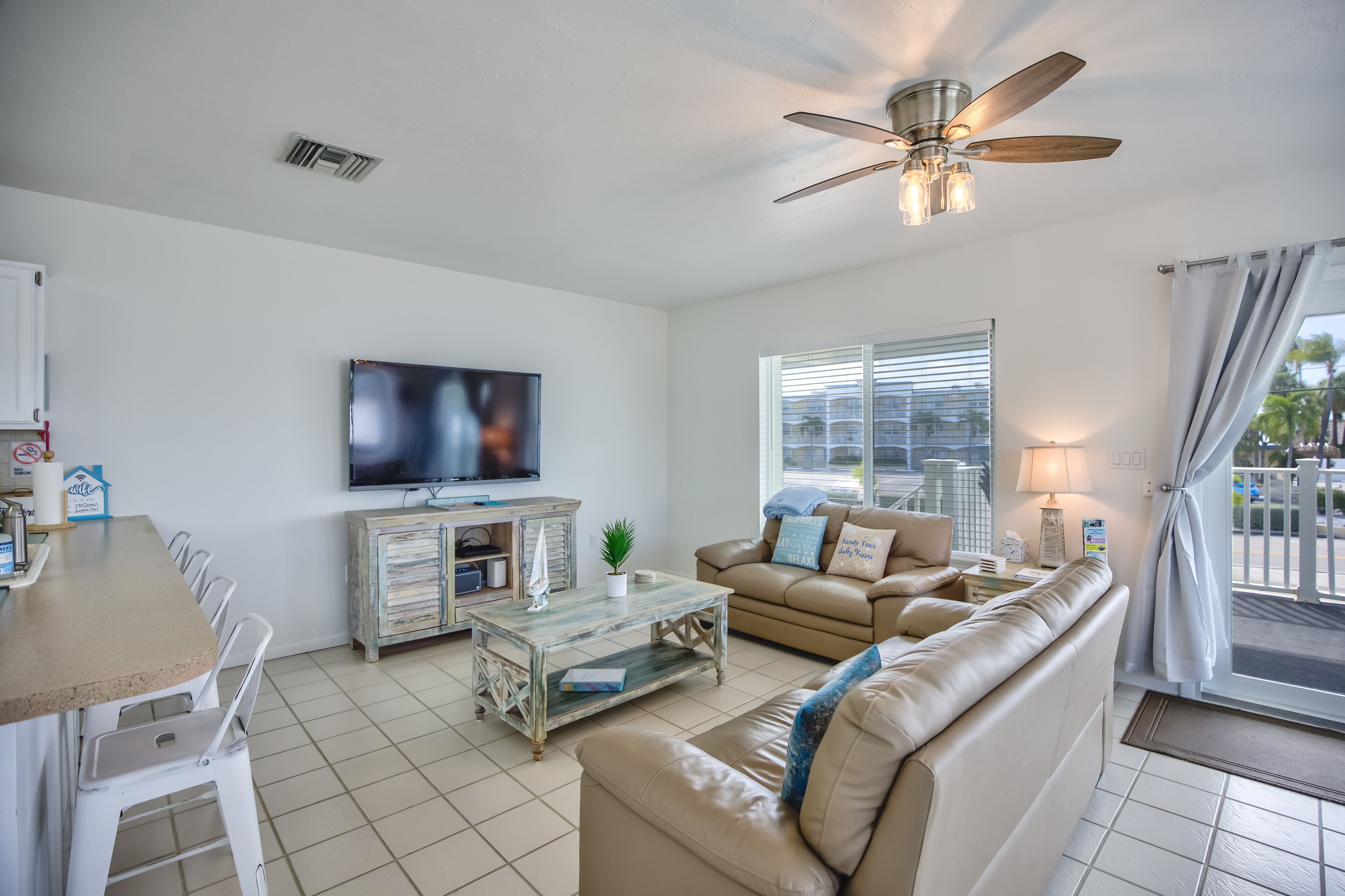 A living room with a TV, sofa, coffee table, and a ceiling fan.