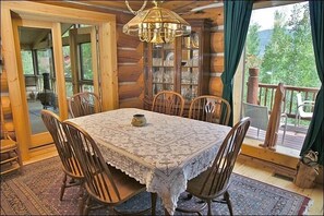 Enjoy meals in this charming dining area with a large table, wooden chairs, and a chandelier.