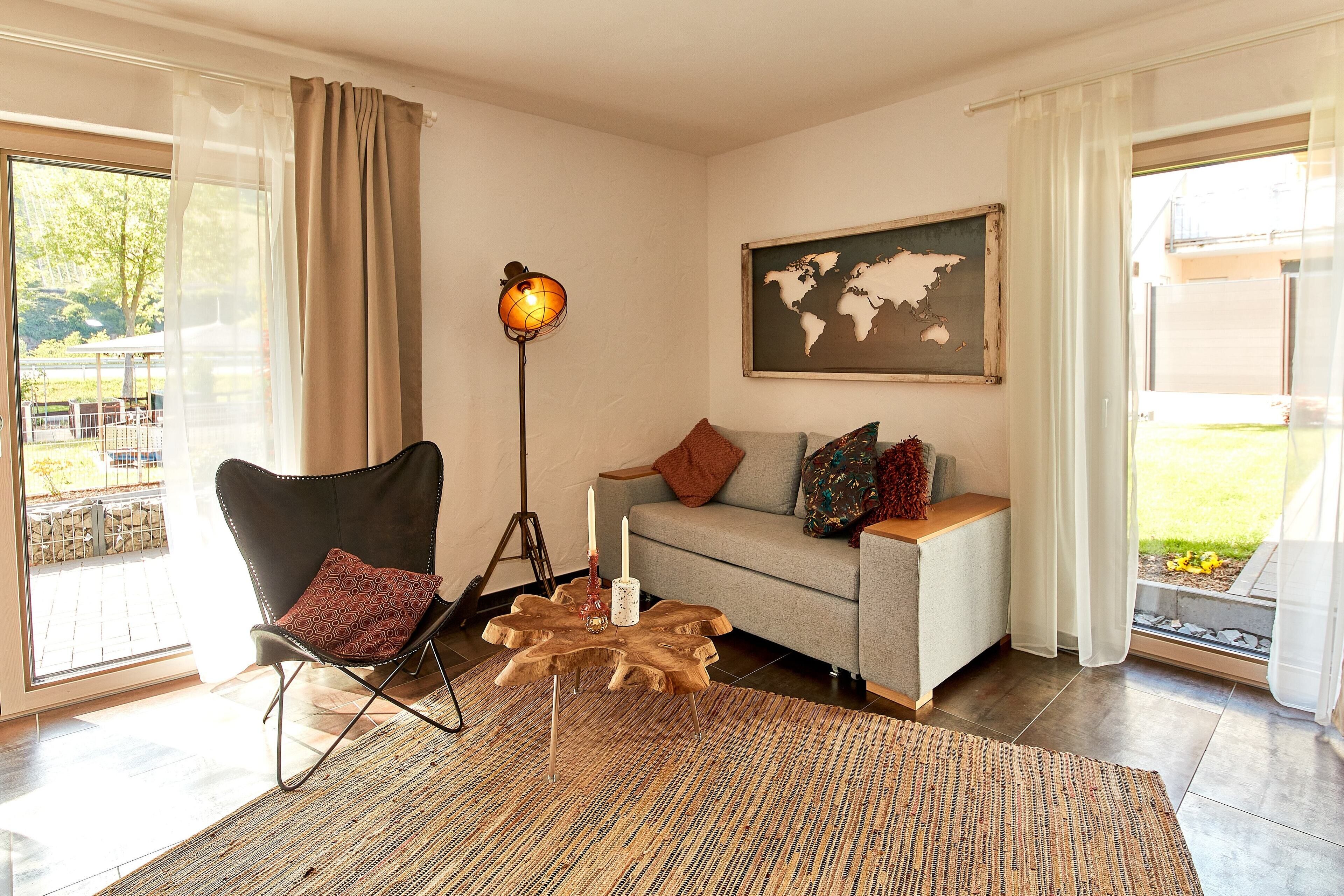 A living room with a modern chair, a sofa, a wooden coffee table, a floor lamp, and a world map on the wall.