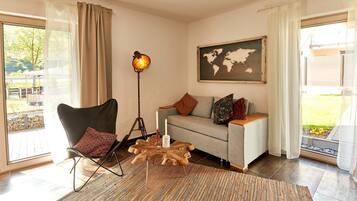 A living room with a modern chair, a sofa, a wooden coffee table, a floor lamp, and a world map on the wall.