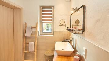 Un bagno con una scala in legno, uno sgabello, un lavandino e una finestra con persiane.