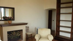 A living room with a fireplace, a chair, a sofa, and a wooden bookshelf. - THE TERRACE - Apartment in Villa from the beginning of the 20th century (Lastra a Signa)