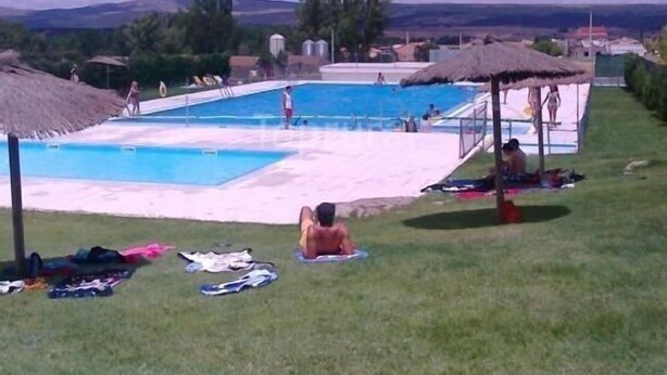 Ein Schwimmbeckenbereich mit mehreren Pools, Sonnenschirmen und Personen.