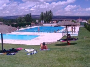 Un área de piscina con varias piscinas, sombrillas y personas.