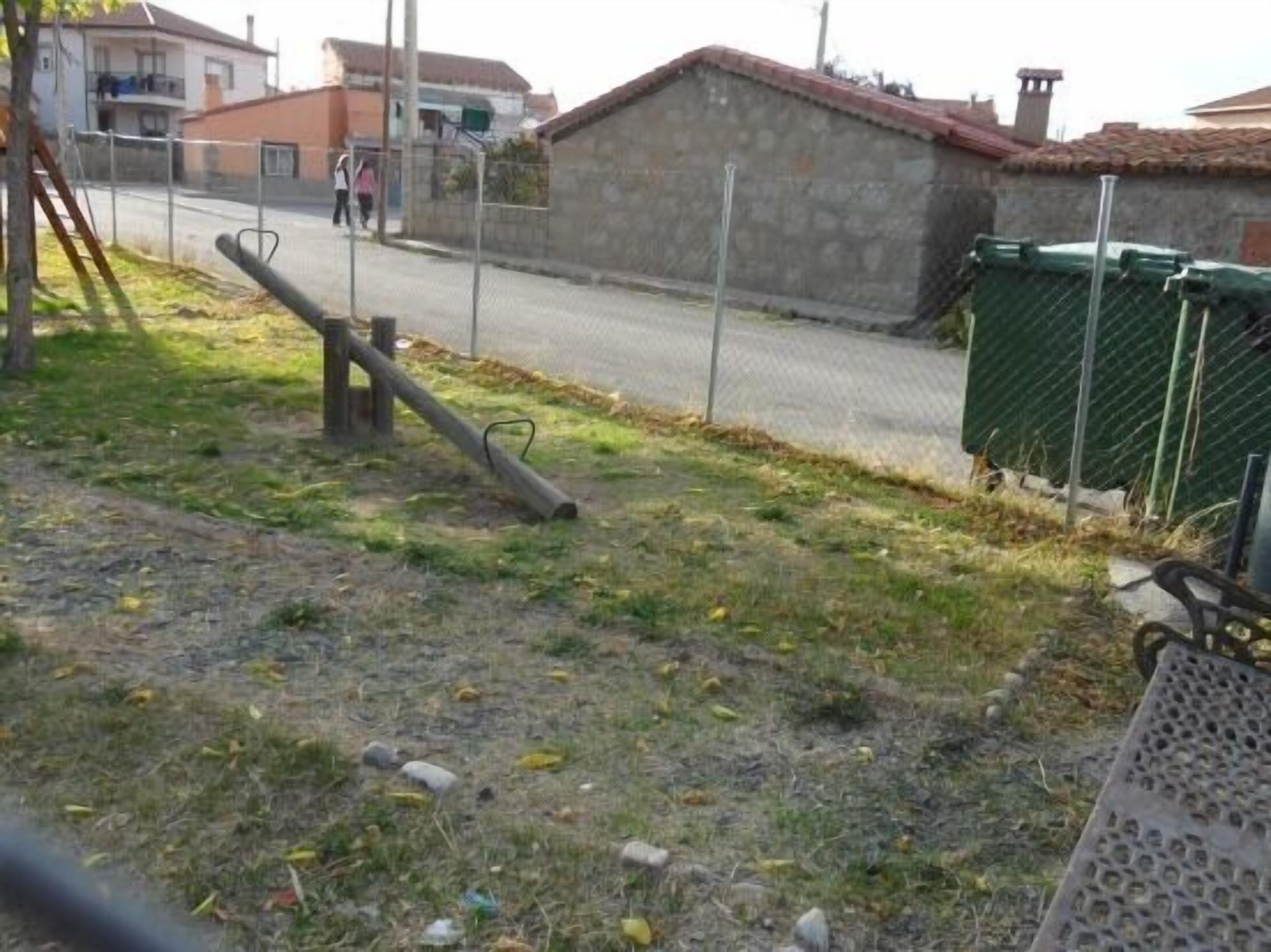 Un quartiere residenziale con una strada asfaltata, un edificio in pietra e un cortile recintato.