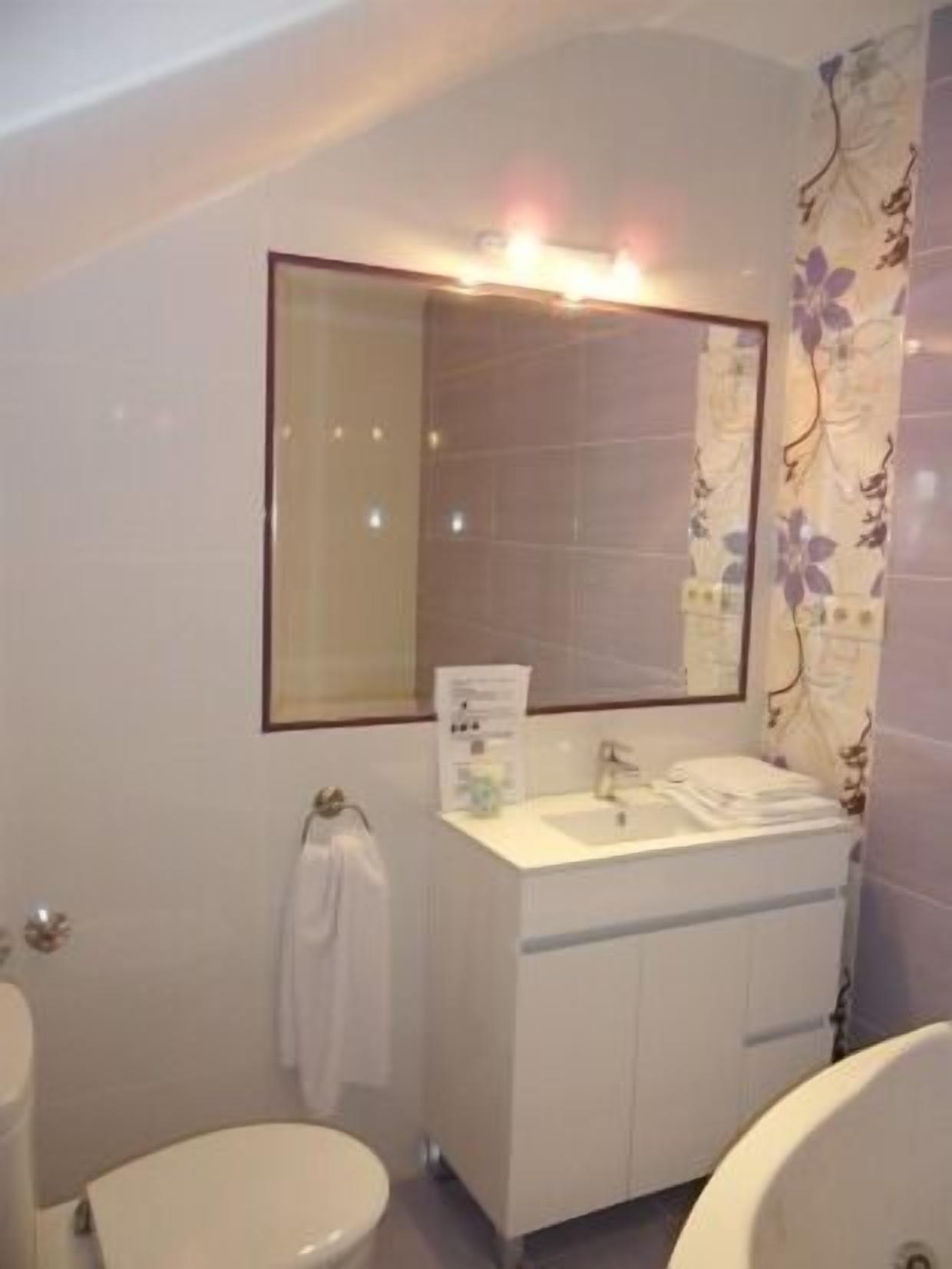 A bathroom with a white sink, mirror, and two toilets.