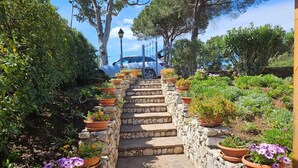 Una scala in pietra con vasi in terracotta pieni di fiori che conduce a un portico.