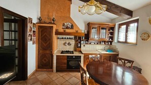 Cucina con mobili in legno, schienale piastrellato, piano cottura e tavolo da pranzo con sedie.