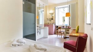 A hotel room with a bed, a desk, a chair, a bathroom, and a window with a view. - Rome: Delightful tiny apartment close to the Colosseum (Roma)