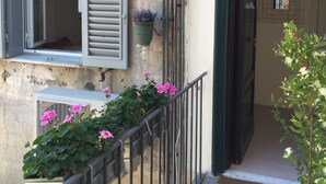 A building with a balcony, a window with shutters, a potted plant, and a door. - Rome: Delightful tiny apartment close to the Colosseum (Roma)