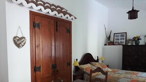 Ein Schlafzimmer mit einem Holzschrank, einem Bett mit floralem Bettzeug, einem Nachttisch und einer Pendelleuchte.