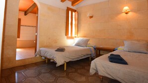 A room with two beds, a wooden ceiling, a stone wall, and a window with curtains. - Can Bril, Wifi free, Private pool, Garden, 15 Minutes From the beach Es Trenc (Mallorca)
