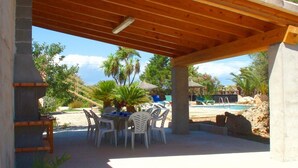 An outdoor patio with a wooden pergola, a pool, and palm trees. - Can Bril, Wifi free, Private pool, Garden, 15 Minutes From the beach Es Trenc (Mallorca)
