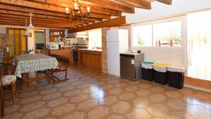 A kitchen with wooden beams, a dining table with a patterned tablecloth, a sink, and a window with blinds. - Can Bril, Wifi free, Private pool, Garden, 15 Minutes From the beach Es Trenc (Mallorca)