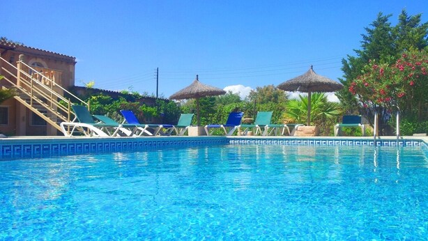 A swimming pool with lounge chairs and thatched umbrellas. - Can Bril, Wifi free, Private pool, Garden, 15 Minutes From the beach Es Trenc (Mallorca)
