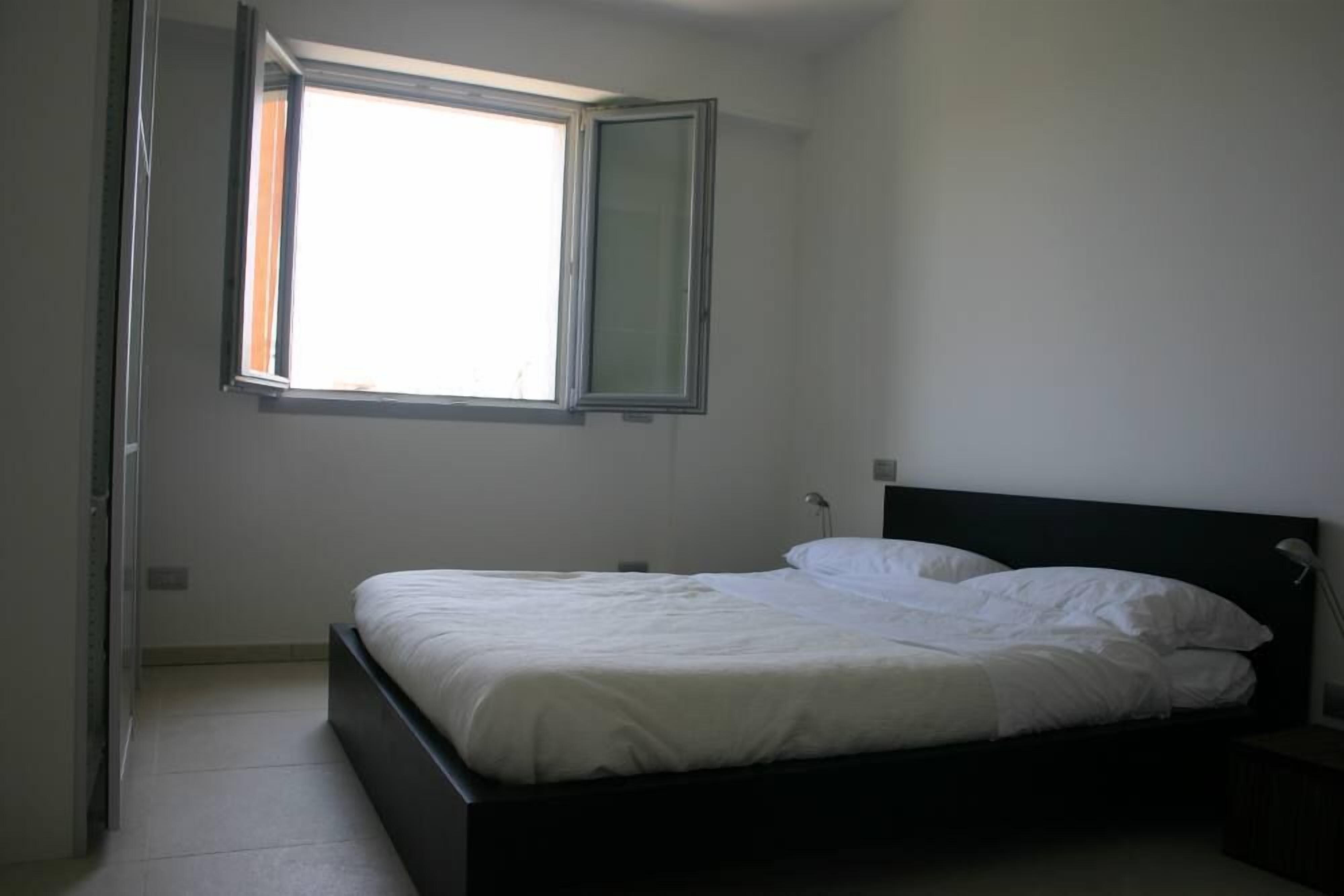 Une chambre avec un lit simple, une fenêtre et une table de chevet.