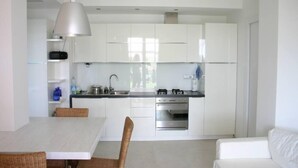 A modern kitchen with white cabinets, a dining table, and a white sofa. - Apartment/ flat - Pietra Ligure (Pietra Ligure)