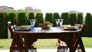A wooden dining table set outdoors with chairs, a bowl of fruit, and wine glasses. - Apartment/ flat - Pietra Ligure (Pietra Ligure)