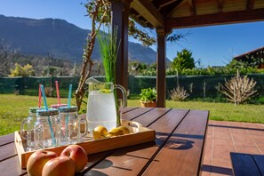 A wooden picnic table with a pitcher of water, mason jars, lemons, and apples.