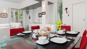 A dining area with a glass table, red chairs, white plates, and a basket of bread. - Overview exclusive seaside villa in Sorrento Peninsula (Massa Lubrense Sorrento)