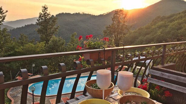Ein Esstisch mit Schüsseln voller Speisen und Gläsern, mit Blick auf einen Pool und eine schöne Berglandschaft.
