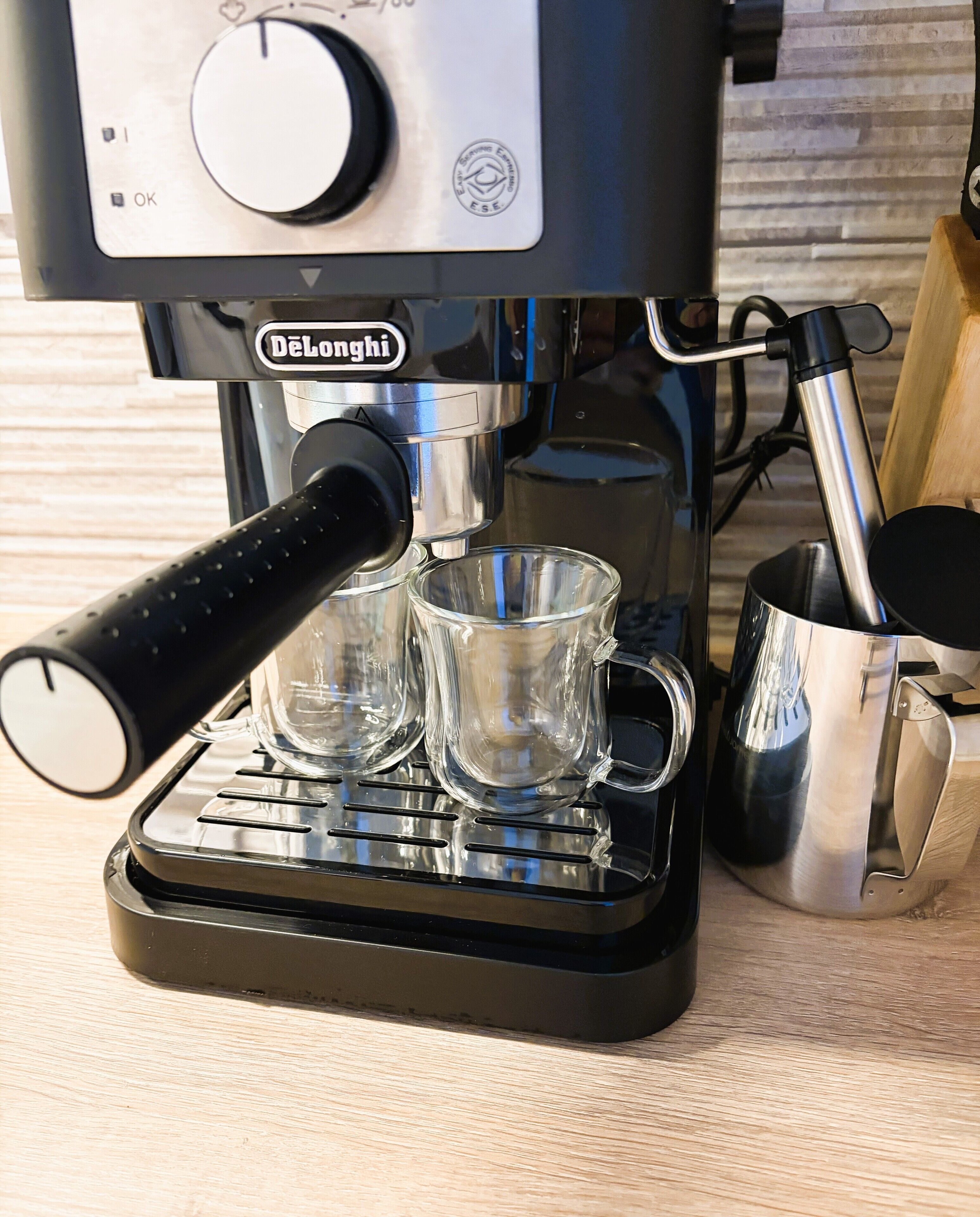Una máquina de espresso DeLonghi con un molinillo de café y dos tazas en su bandeja de goteo.