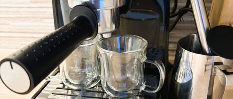 Una máquina de espresso DeLonghi con un molinillo de café y dos tazas en su bandeja de goteo.