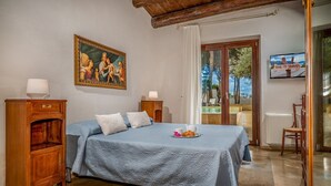 A bedroom with a bed, a painting, a TV, and a view of the outdoors. - Casale Domè 14+2, Emma Villas (Ciavolo)