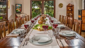 A long dining table set for a meal with a roasted chicken centerpiece, surrounded by chairs and wine glasses. - Casale Domè 14+2, Emma Villas (Ciavolo)