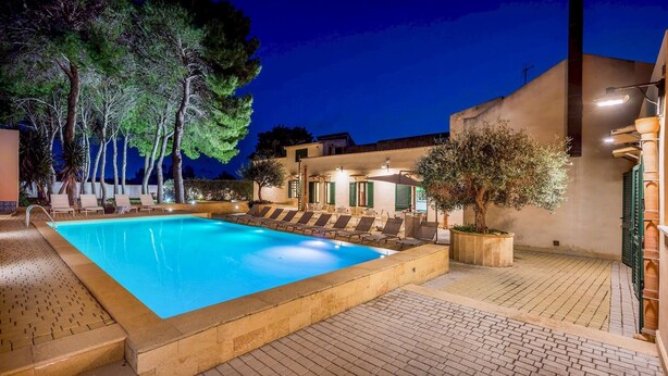 A swimming pool with lounge chairs and a building with a balcony. - Casale Domè 14+2, Emma Villas (Ciavolo)