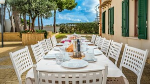 An outdoor dining area with white chairs and tables, a coffee pot, and a glass of water on the table. - Casale Domè 14+2, Emma Villas (Ciavolo)