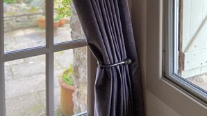 A window with a dark curtain and a striped awning.
