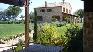 Una casa de piedra con vistas a un jardín, una mesa de madera y sillas.
