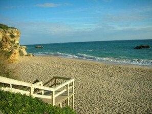 A beach with a wooden walkway leading to a cliff. - Apartment (Albufeira)
