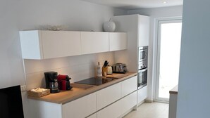A modern kitchen with white cabinetry, a built-in oven, a coffee maker, and a toaster.
