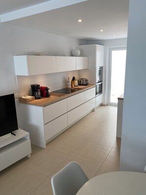 A modern kitchen with white cabinetry, a built-in oven, a coffee maker, and a toaster.