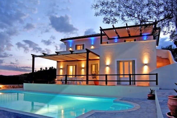 Vue de la villa et de la piscine de nuit